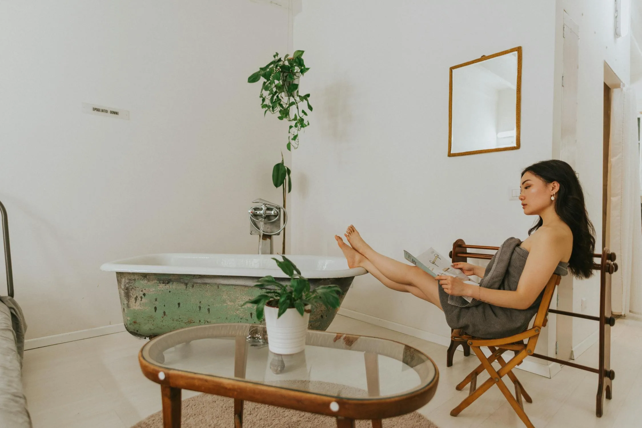 Artificial green plants placed on a bathroom table next to the bathtub