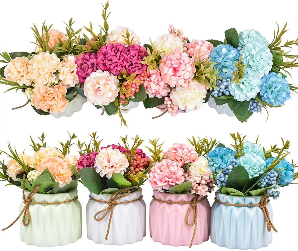 Four colorful mini artificial hydrangea flower pots lined up on a white desk