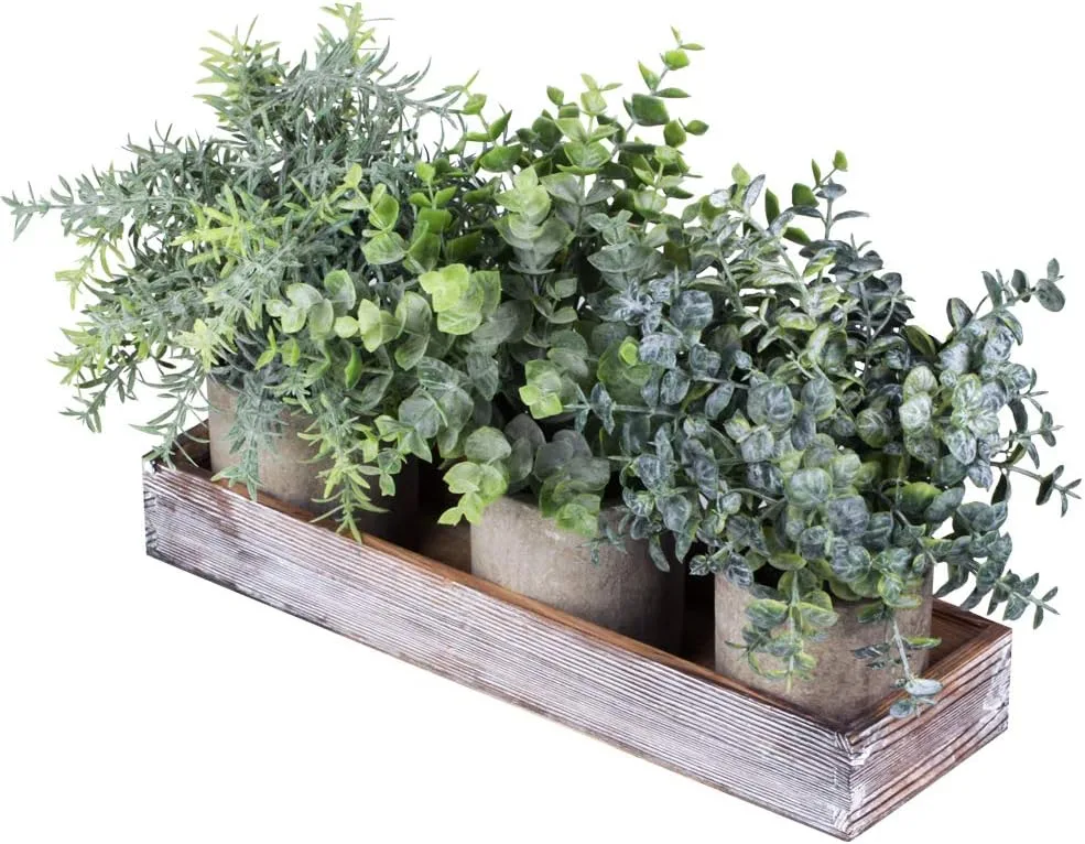 Set of three artificial eucalyptus and rosemary plants in a wooden box on a modern office desk