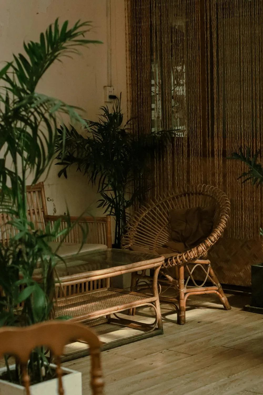 A modern living room showcasing trending artificial plants, including a large faux tree and hanging greenery.